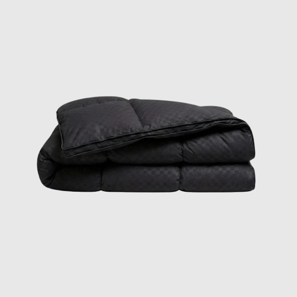 Folded black quilt on a light gray background